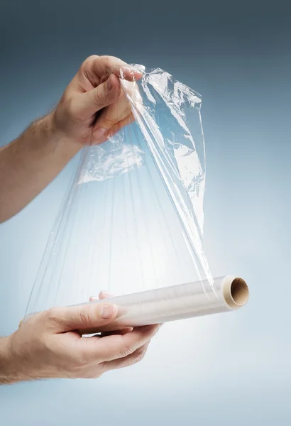 Человек, держащий рулон пластиковой пленки — стоковое фото