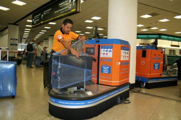 Процесс платной упаковки чемодана в аэропорту